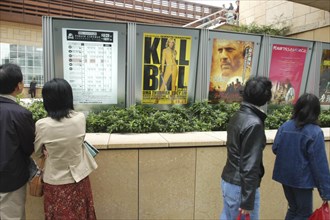 JAPAN, Tokyo, Roppongi, Roppongi Ark Hills Ark Tower. Japanese looking at poster for foreign film