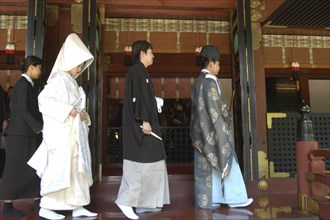 JAPAN, Honshu, Tokyo, Nezu. Shinto priest leads newly married couple out of Nezu Jinja shrine after