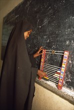 SOMALILAND, Hargeisa, Ali Osman Primary School.  Girl using abacus in classroom.