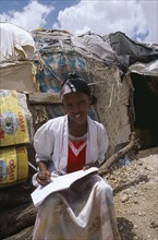 SOMALILAND, Hargeisa, Girl doing homework outside hut in Kandahar IDP camp.