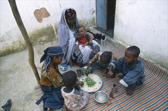 SOMALIA, Baidoa, Woman and children eating lunch from communal dish using the right hand.  At a