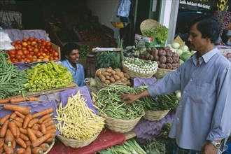 SRI LANKA, Colombo, Pettah District. Customer at a market stall selling vegetables