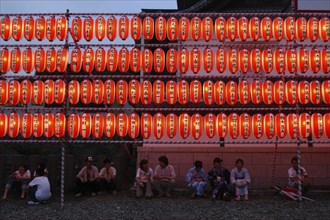 JAPAN, Chiba, Narita, Festival goers at the Gion Matsuri rest under rows of illuminated chochin