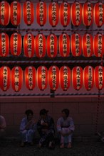 JAPAN, Chiba, Narita, "Teenage girls in yukata, summer kimono, sit beneath chochin lanterns each