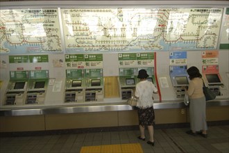 JAPAN, Honshu, Tokyo, Ueno train station with women buying train tickets from vending machines with