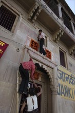 INDIA, Uttar Pradesh, Varanasi , Deep Diwali Festival with teenage boys climbing a doorway to