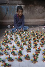 INDIA, Uttar Pradesh, Varanasi, Young boy selling figurines of Kala Bhairava outside Kala Bhairava