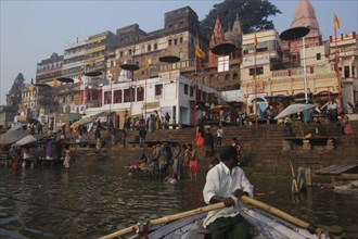 INDIA, Uttar Pradesh, Varanasi, A boatman bringing his boat into Dashaswamedh Ghat with early