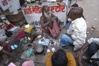 INDIA, Uttar Pradesh, Varanasi, Godaulia Area. A roadside dentist works on a patients dentures