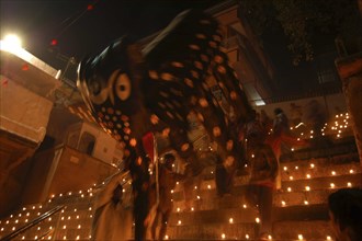 INDIA, Uttar Pradesh, Varanasi, Deep Diwali Festival. Men carry a paper statue of the Hindu God