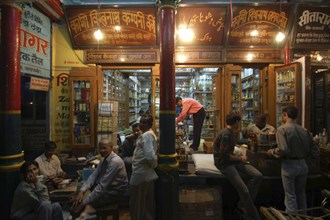 INDIA, Uttar Pradesh, Sarnath, Men chatting outside a shop at night near the chowk