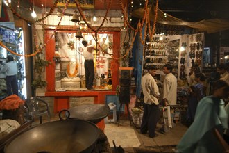 INDIA, Uttar Pradesh, Varanasi, Dasaswamedh Ghat. A man cleans the shrine of a Hindu saint in the