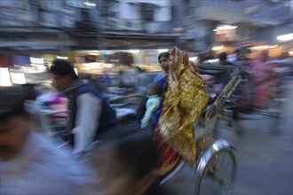 INDIA, Uttar Pradesh, Varanasi, The Godaulia intersection. A passing rickshaw with two women in