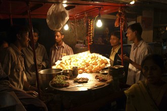 INDIA, Uttar Pradesh, Varanasi, Young men buying snacks on the road at night