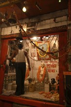 INDIA, Uttar Pradesh, Varanasi, Dasaswamedh Ghat with a man cleaning a shrine to a Hindu Saint