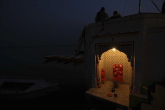 INDIA, Uttar Pradesh, Varanasi, Near Hanuman Ghat. A Hanuman Shrine on the Ganges River at night