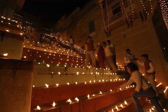 INDIA, Uttar Pradesh, Varanasi, Deep Diwali Festival. People lighting oil lamps on the steps