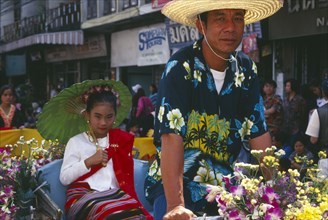 THAILAND, Chinag Mai, Young girl riding rickshaw driven by man in the Flower Festival Parade