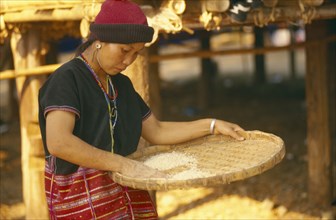 THAILAND, Chiang Mai, Sgaw Karen woman using a bamboo tray to sift pounded rice