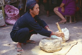 THAILAND, Chiang Mai Province, Yao man grinding corn in a stone hand grinder