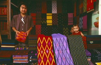 MYANMAR, Kachin State, Myitkyina, Kachin woman selling sarongs and other textiles at the market