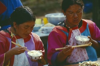 THAILAND, Chiang Rai Province, Doi Lan, Two Lisu women eating at the village priests house for the