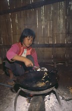 THAILAND, Chiang Rai Province, Doi Lan, Lisu girl putting cooked bamboo grubs in a bowl in her