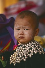 THAILAND, Chiang Rai Province, Huai Khrai, Portrait of a Lisu infant boy wearing New Year silver