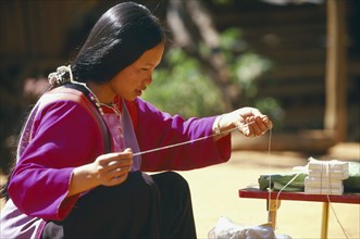 THAILAND, Chiang Mai Province, Bahn Mae Phaem, Lisu woman preparing string to be tied on familys
