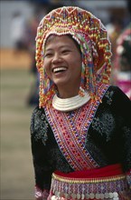 THAILAND, Chiang Mai, Hmong New Year. Young blue Hmong woman in her New Year finery laughing