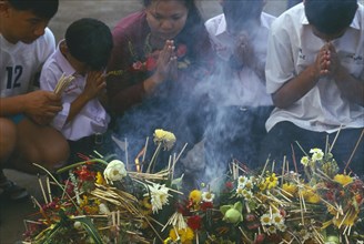 THAILAND, Chiang Mai, Wat Jedi Luang, Inthakhin Ceremony. People praying in front of offerings of