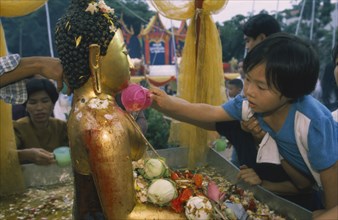 THAILAND, Chiang Mai, Wat Jedi Luang, Inthakhin Ceremony. Young boy bathing Phra Fon Saen Ha Buddha