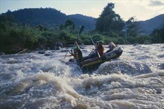 THAILAND, Chiang Mai Province, Western tourists and Thai guides white water river rafting on the