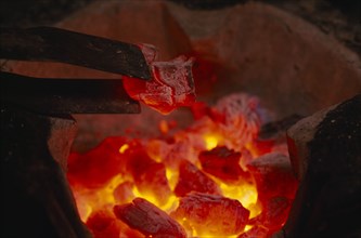 THAILAND, General, Close up of glowing hot coals and tongs in a hibachi Thai charcoal brazier