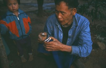 THAILAND, Chiang Rai Province, Doi Lan, Lisu elder reading a pair of chicken wings for oracular