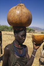 UGANDA, Karamoja, Moroto District, Karamojong woman carrying water gourd on her head.