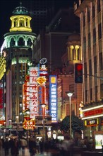 CHINA, Shanghai, Nanjing Road at night with illuminated neon signs and crowds of people in blurred