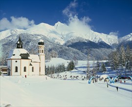 AUSTRIA, Tirol, Seefeld, Church in winter landscape with skiing competition taking place in middle