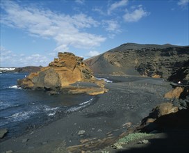 SPAIN, Canary Islands, Lanzarote, El Golfo.  Black volcanic sand beach and coastline with a few