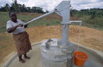 LIBERIA   , Margibi, Kakata, Young woman pumping clean water from UNHCR supplied water pump.