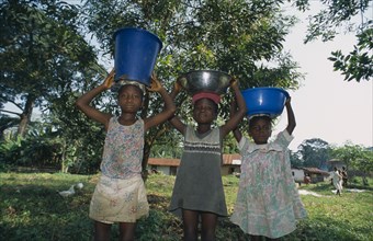 LIBERIA   , Nimba, Saclepea, Three children carrying water vessels on their heads.