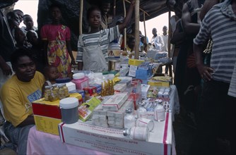 LIBERIA   , Nimba, Saclepea, Woman behind stall with display of medical supplies surrounded by