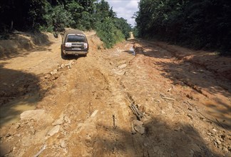 LIBERIA   , Nimba, Zinakopa, Car on unmade road with deep ruts through mud in foreground.