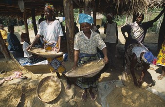LIBERIA   , Margibi, Wohn, Women winnowing grain.