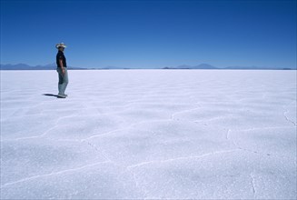 BOLIVIA, Altiplano, Potosi, Salar de Uyuni.  Person walking across vast expanse of salt lake.