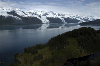 USA, Alaska, College Fjord, View over trees and calm waters of the bay toward snow capped mountain