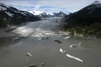 USA, Alaska, Juneau, View over murky waters and valley leading toward snowcapped mountain peaks