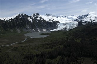 USA, Alaska, Prince William Sound, View over tree covered landscape toward waters and snow capped