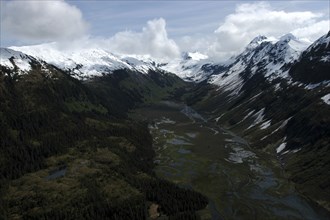USA, Alaska, Prince William Sound, Mountainous tree covered valley with snow capped peaks