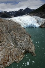 USA, Alaska, Tracy Arm Fjord, View over rocky edged waterway toward icy slope and mountain peaks